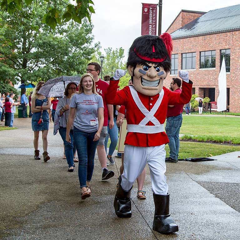 Students walking with Gus the Grenadier in front of the IUS Library.